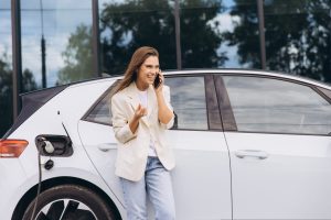 Young,Woman,Enjoying,A,Phone,Call,While,Charging,Her,Electric